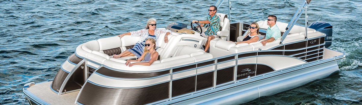 There is a group of people relaxing on a Bennington pontoon while one person drives.